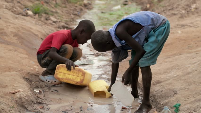 UGANDA, GULU - 15 February 2017: Children fetching dirty drinking water for both domestic and animal use. African children using a large bottle to fill water from a dirty water source