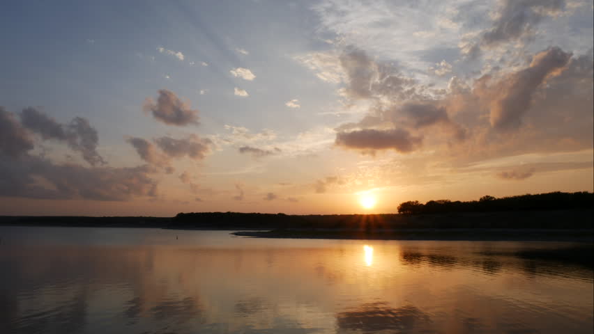 Time Lapse of Sunset Behind Small Hill Reflecting on the Water