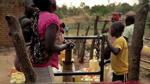 UGANDA, GULU - 15 February 2017: African children filling up a plastic container at a water well in Rural Uganda, Africa