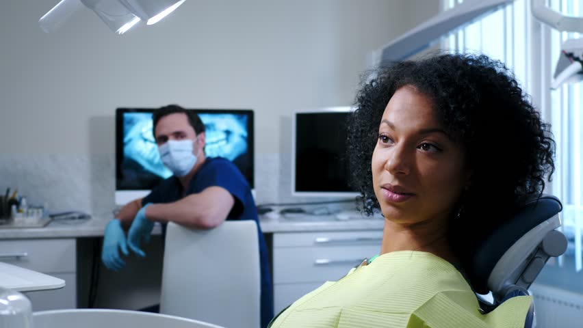 Man dentist showing x-ray results to his pacient. | Shutterstock HD Video #1009368596