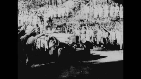 CIRCA 1943 - Adolf Hitler is driven in a military parade and warplanes and tanks are shown in Nazi Germany.