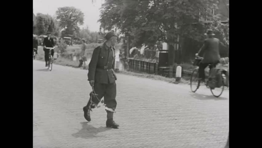 CIRCA 1940s-Troops march and horse drawn wagons travel down streets in the Netherlands.