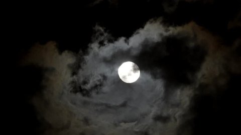 Full moon on a dark night with clouds moving over it