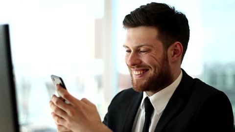 Happy business man typing on phone. Writing message on phone. Young man smiling