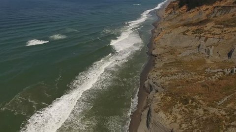 Panning over a sandy beach with clay cliffs วิดีโอสต็อก