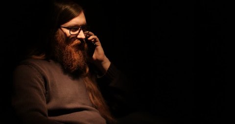Bearded man talking on the phone in the darknes