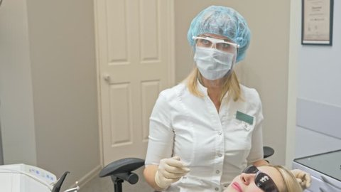 Doctor used special Dental Intraoral Check Digital Micro Camera to exam teeth. Dentist and assistant work in protective masks. Dentist is treating patient in modern dental office.