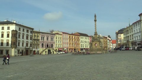 Baroque plague column called Marian on the Dolni square in the city of Olomouc. National cultural monument from 1723, architect Jan Sturmer, people walk and sit on bench, historical houses monument