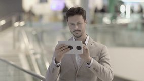 Lifestyle Portrait of Attractive Male Entrepreneur Searching the Web on Tablet Touchscreen. Shot on Red Epic.