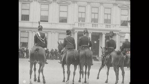 CIRCA 1912 - A group of mounted guardsmen lead a procession to Noordeinde Palace.
