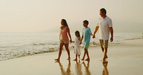 Young mixed race family on the beach at sunset