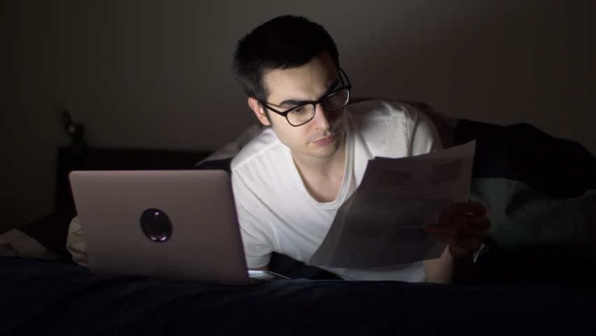 Man at night in his bed with a laptop working on a project late