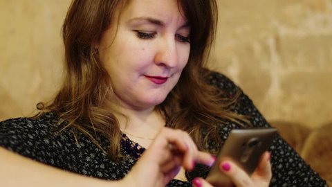 Adult woman uses smart phone near frayed wall, closeup