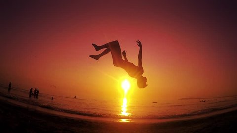 Parkour free runner runs and jumps backflip at summer beach sunset. Steadicam SLOW MOTION shot