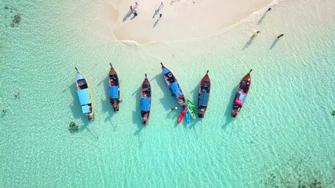 Aerial view of Long Tail Boats floating on crystal water along the sand beach in Thailand.Summer Aerial View footage in 4K.