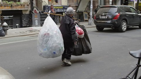 NEW YORK - MAY 17, 2015: homeless Asian lady carrying plastic bags filled with empty soda cans, slow motion 4K Manhattan NY. Homelessness is a major problem in New York City, USA.