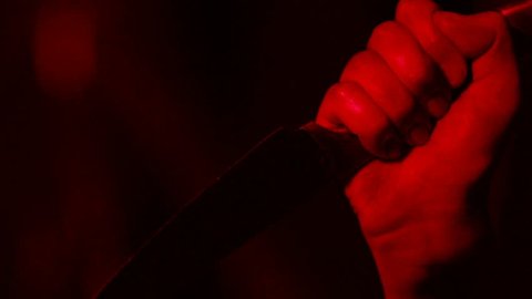 Male hand killing with knife, cold-blooded massacre, scary thriller, closeup