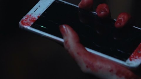 Woman holds broken smartphone in blood, victim of maniac tries to call police