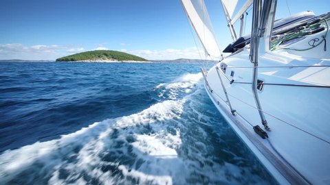 Yacht sailing at the sea of Croatia. Sailboat in windy conditions cruising clear blue ocean water. Large white Yacht with drawn sails / canvas.