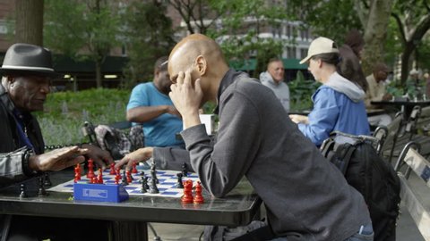 NEW YORK - MAY 17, 2015: panning, steadicam shot of chess tables with speed matches and timers in park in 4K slow motion Manhattan NY. Washington Square Park is a famous public park in NYC, USA.