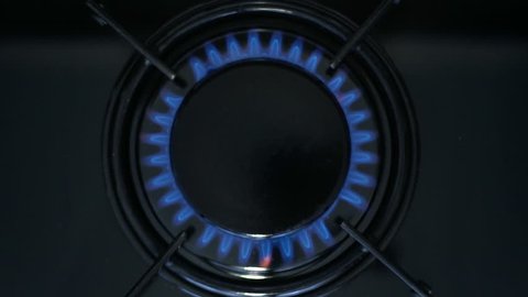 Kitchen burner turning on.Stove top burner igniting into a blue cooking flame.  Natural gas inflammation, close up, slow motion.
