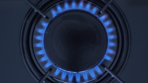 Kitchen burner turning on.Stove top burner igniting into a blue cooking flame.  Natural gas inflammation, close up.
