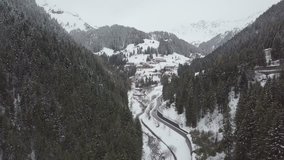 Drone approach to a mountain village in winter snow over the road.