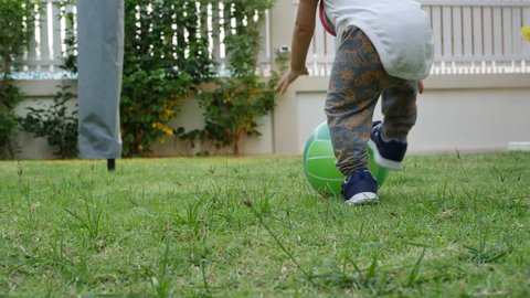 slow-motion, cute child toddle falling on green grass playing ball