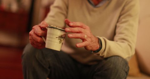 Closeup of hands holding cup of tea at night in living room. Hands of 60 year old man holding cup of tea or coffee