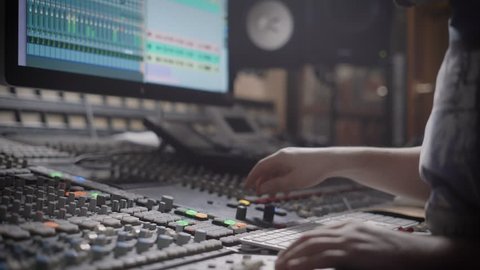 Talanted dj is creating music in a recording studio on a mixing console.