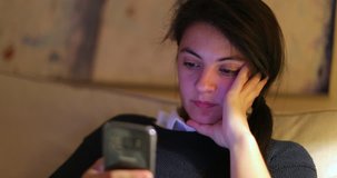 Candid clip of woman using her cellphone. Woman holding her smartphone in living room sofa at night