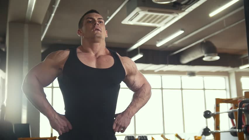 Strong man warming up in front of a mirror in workout room