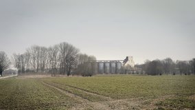 Grain metallic silo building in landscape, big tin seed elevator. Footage of agriculture countryside, farming, husbandry in plain, flat land. 