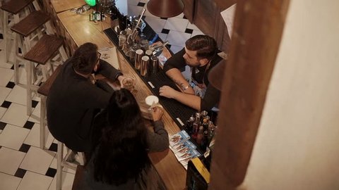 ROSA KHUTOR - FEBRUARY 2018: BAR Shot from above of a man and woman sitting in a bar and having a conversation with a barman. Drinking cocktails. Lovely night.
