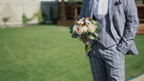 Handsome man holding a bouquet. Groom prepares for a wedding