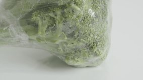 Fresh Brassica oleracea wrapped in cellophane 4K 2160p 30fps UltraHD tilting footage - Packed edible green broccoli close-up slow tilt 3840X2160 UHD video