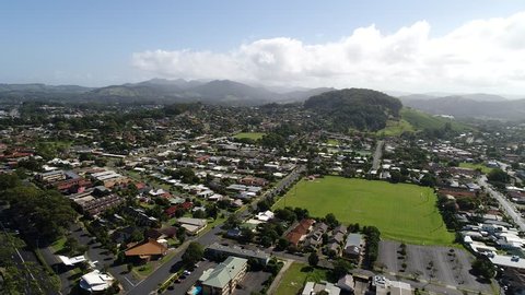 High aerial rotation over Coffs Harbour regional town on NSW Mid North Coast over shopping village in view of mountains and town beaches with marina and harbour.

