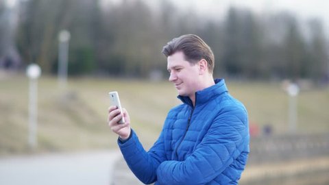 A young attractive man is using a mobile phone at sunset.