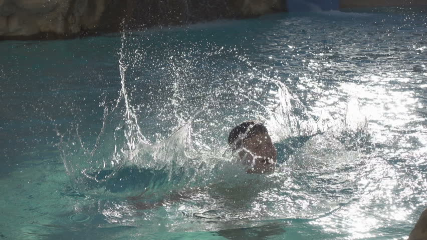 silhouette of boy splashing water in pool, slow motion