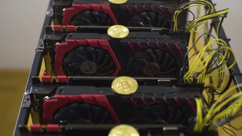 Bitcoins in line on graphics card in mining machine rig, concept cryptocurrency, room interior, tracking, tilt down, rack focus, shallow depth of field, macro, nobody