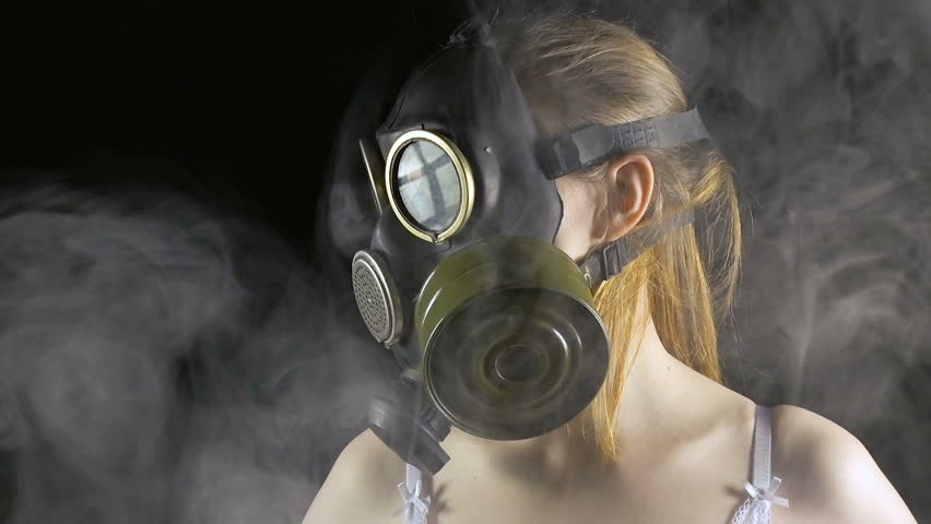 Young woman in gas mask among smoke