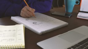 The application developer draws sketches in a notebook. Works remotely from home office. (the drawings are made specifically for the video and do not need property)