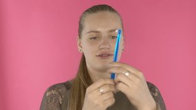 Teenager vlogger recording her daily video blog in front of camera on bright background. Teenage girl with braces talking about tools for cleaning and brushing teeth. Using pink backdrop for vlog.