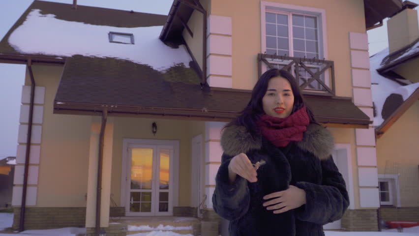 Beautiful brunette stands at the sunset with keys from her new house