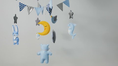 baby mobile with blue hand-stitched animal and bird toys with yellow moon on white wall background