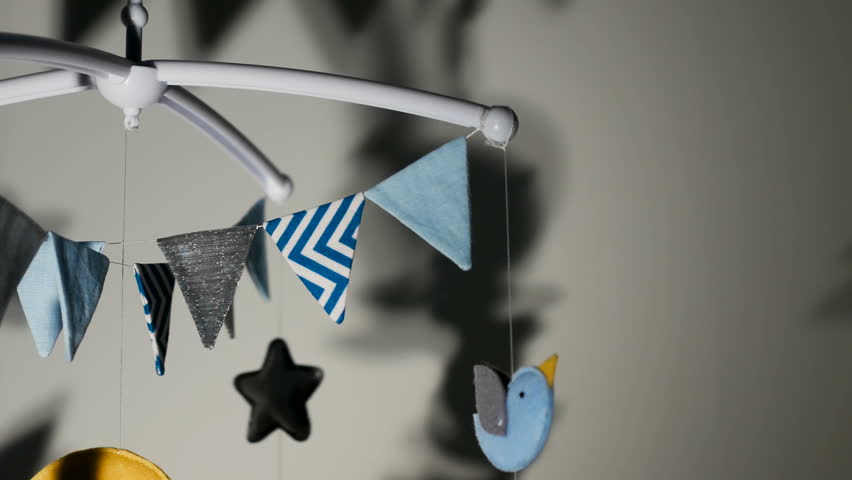baby mobile with blue hand-stitched animal and bird toys with yellow moon on white wall background