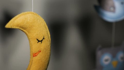 baby mobile with blue hand-stitched animal and bird toys with yellow moon on white wall background