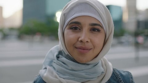 portrait of young independent muslim woman looking confident at camera wearing hijab headscarf in urban city at sunset enjoying lifestyle Arkivvideo
