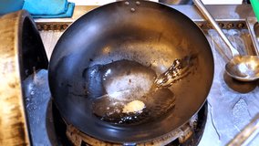 Slow motion (60fps) footage of a raw egg in a hot Wok, a traditional base for stir fry dishes.