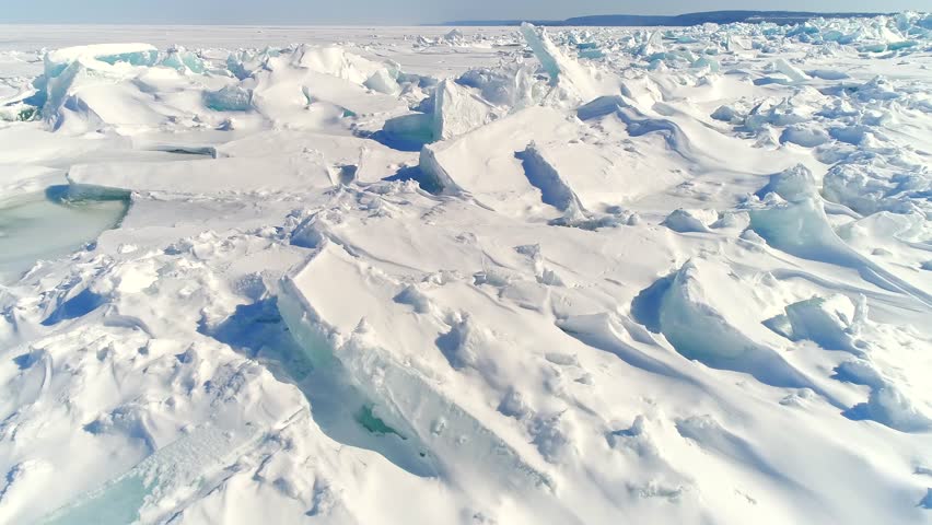 Low aerial flight over scenic, surreal jagged ice shoves on the shore of Door County Wisconsin, created by high winds in Springtime.